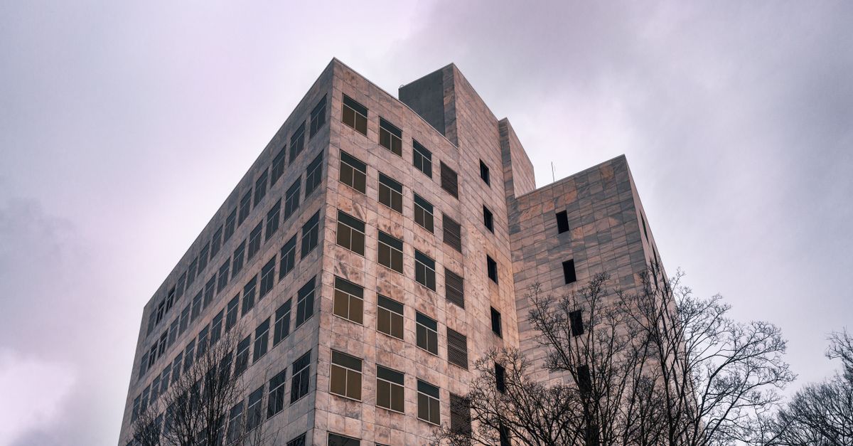 A wide-angle exterior view of a modern American state courthouse building under an overcast sky, calm and formal atmosphere, cinematic soft lighting, no visible writing or sign, no people in focus