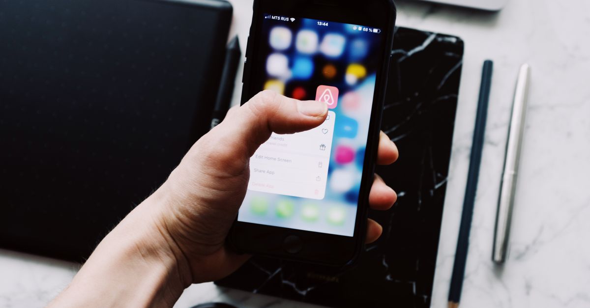 A close-up of a person holding a smartphone showing a generic finance app interface with abstract colored balance bars, soft ambient indoor lighting, no visible writing or symbols, shallow depth of field, realistic Korean home setting in the background